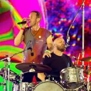 Coldplay performing on stage at Wembley Stadium.