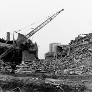Three men watch as the demolition continues