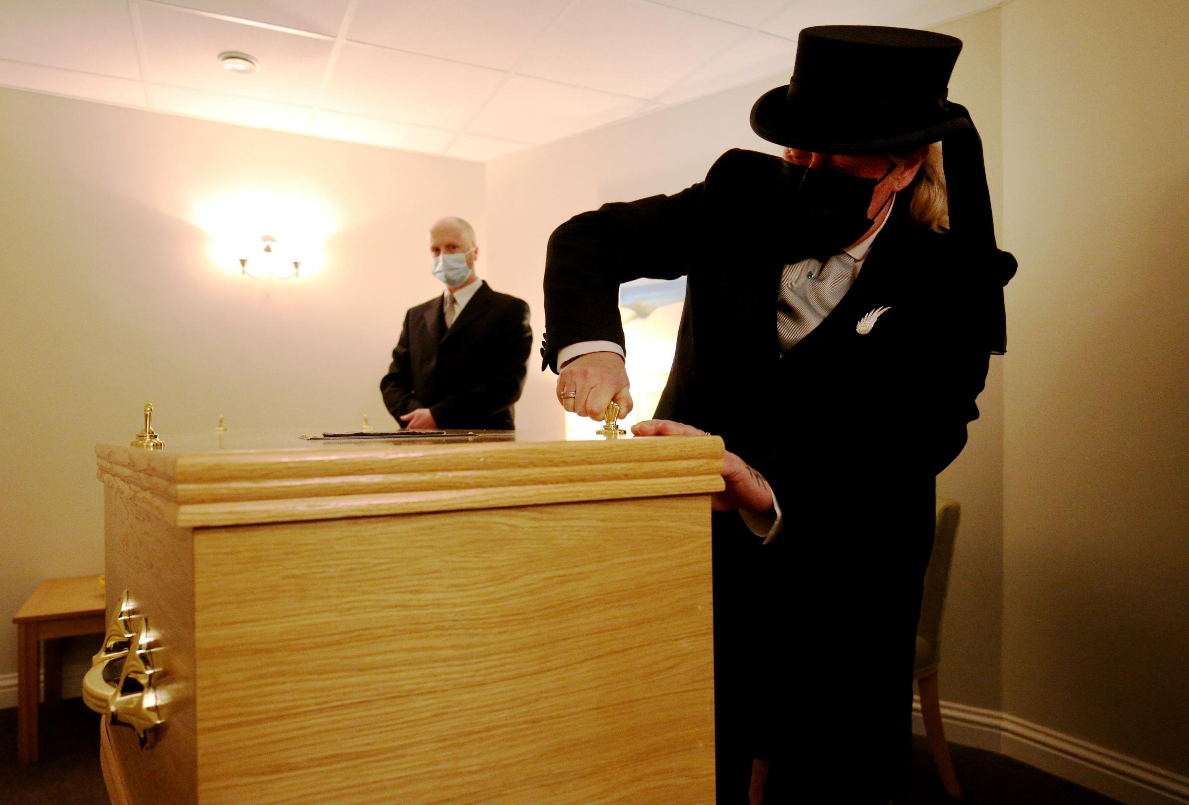 Funeral Director Colette Sworn (right) secures the lid of a coffin as part of her preparations. Photo: PA