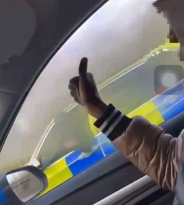 The driver can be seen giving the thumbs-up to an armed officer pointing a gun at them. Credit: Twitter/@CrimeLdn