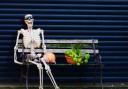 A skeleton takes a break on a park bench