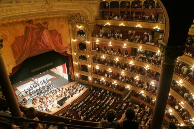 Watford Observer: A grand theatre with people watching an orchestra. Credit: Canva