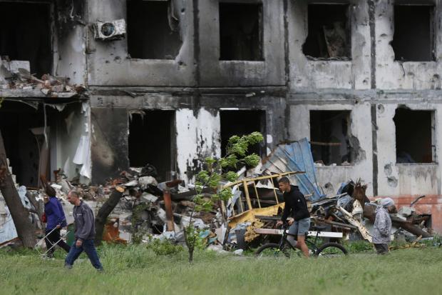 People walk past a destroyed building in Mariupol