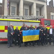 Firefighters Lee Addington, Paul Redhead and Dan Collier at the start of their journey holding the Ukraine flag (left to right). Picture: Hertfordshire County Council