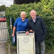 Carol (left) and John (right) stand next to the sign that let him know Watford Observer was running a story on the messages. Picture: Warren Dell Primary School